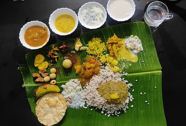 The grand Onam feast, called Sadhya, is a true showcase of vegetarian delicacies. Often featuring over 24 dishes, this elaborate meal is traditionally served on a banana leaf in a specific sequence. Courtesy: Wikimedia