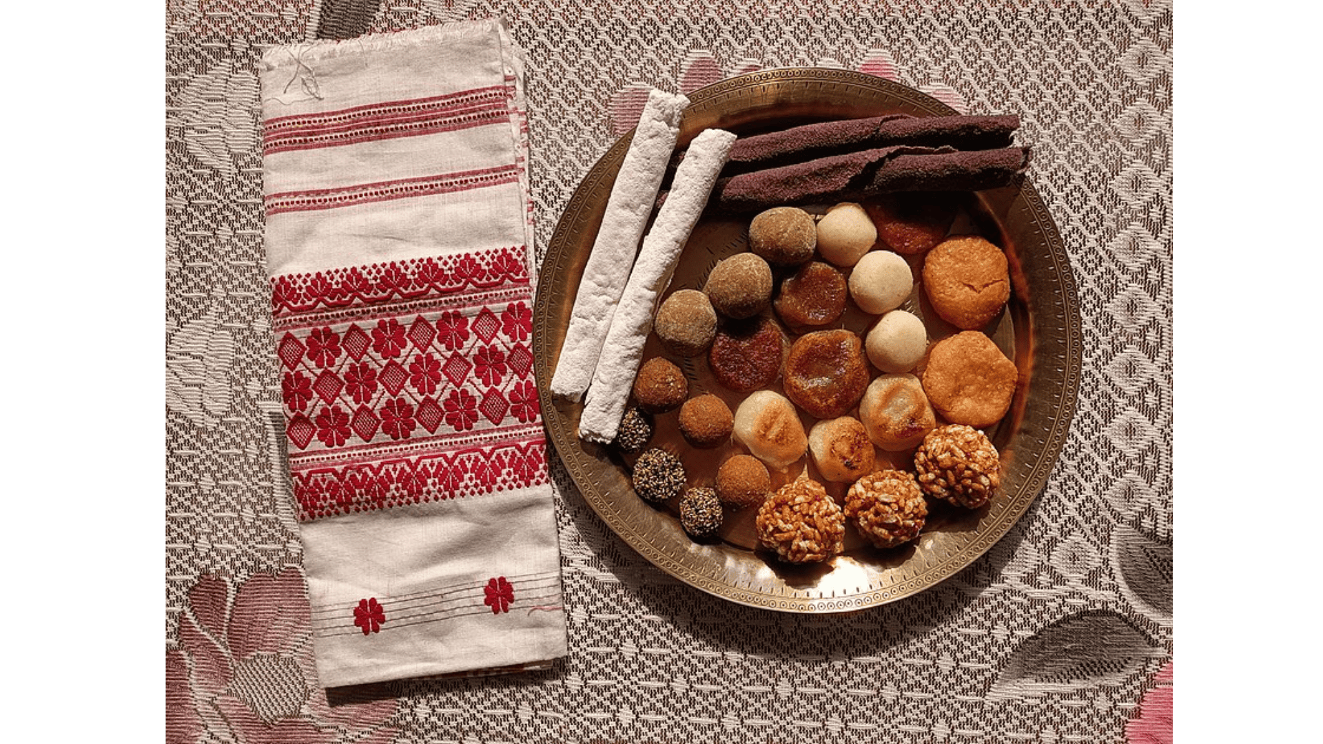 Bihu festival food celebrates Assam’s rich flavours with dishes like pitha, larus, and jolpan—handmade treats crafted from rice, coconut, sesame, and jaggery, symbolising warmth and abundance. Courtesy: Wikimedia