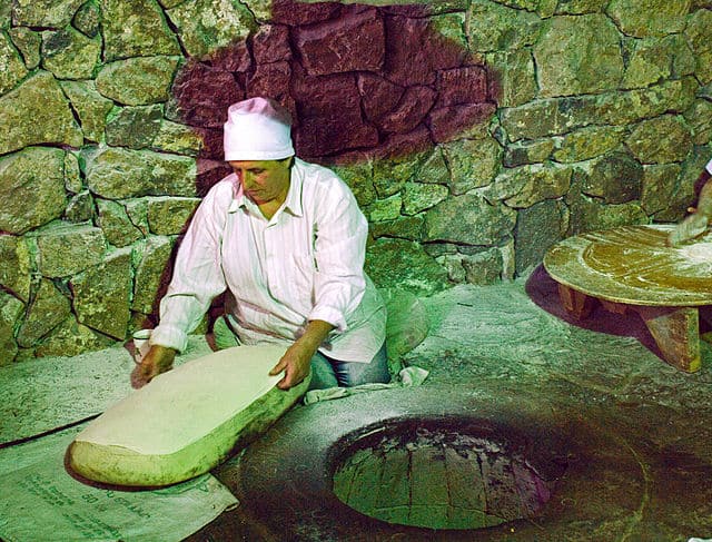 Artisan at work crafting traditional lavash bread in a stone oven. Image Courtesy: Shaun Dunphy, Wikimedia